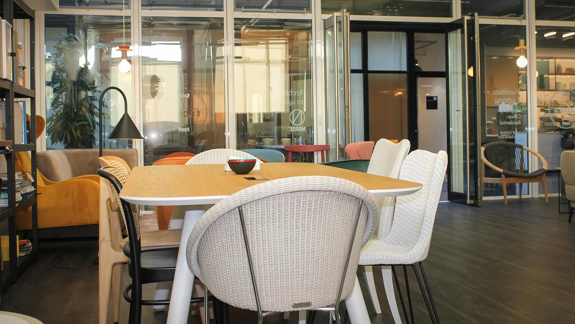 chic dining ensemble showcasing lloyd loom chairs with cane back, a stylish dining table and a floor lamp featuring in the background